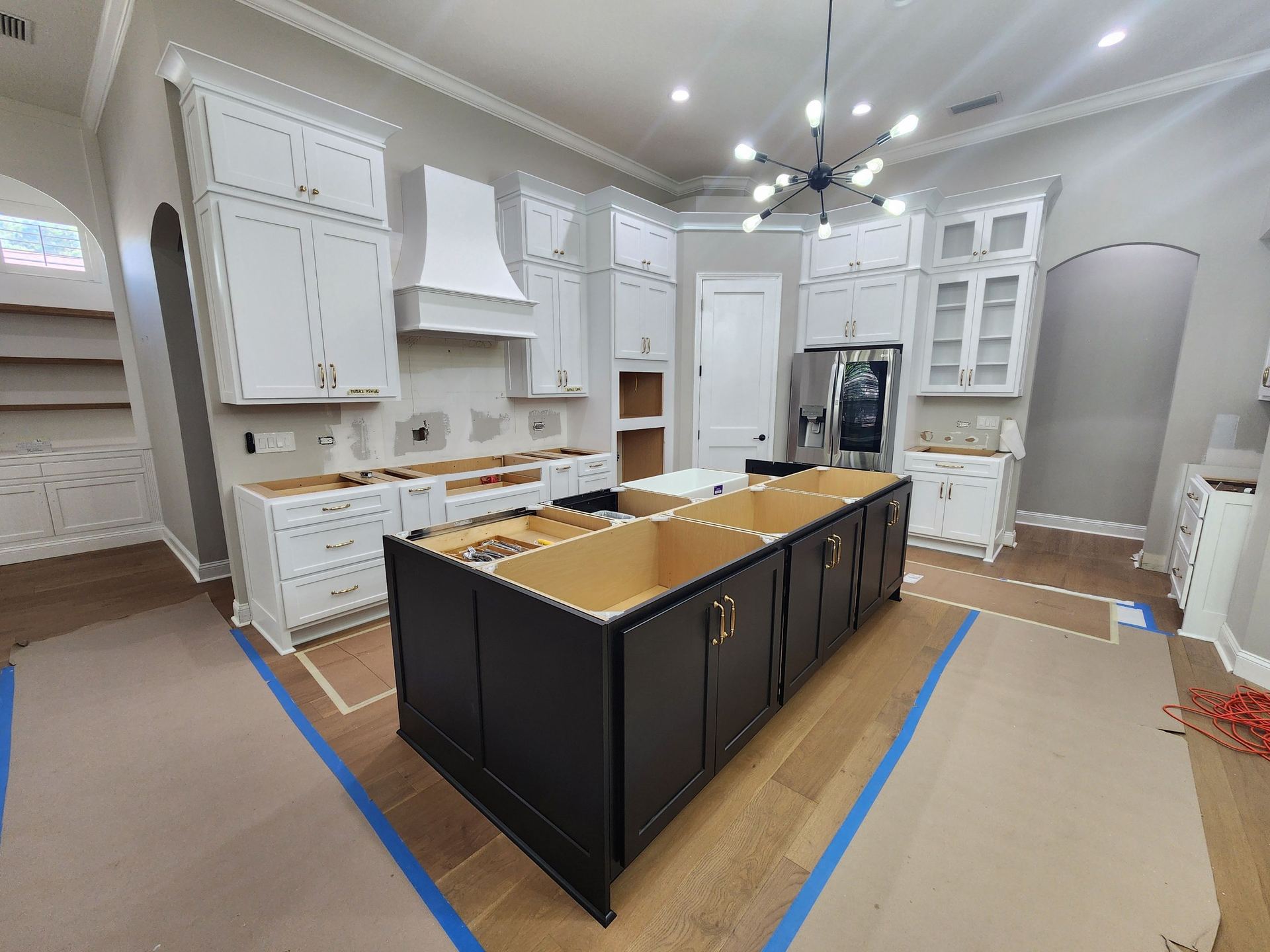 Kitchen during installation with white cabinets and black island in progress