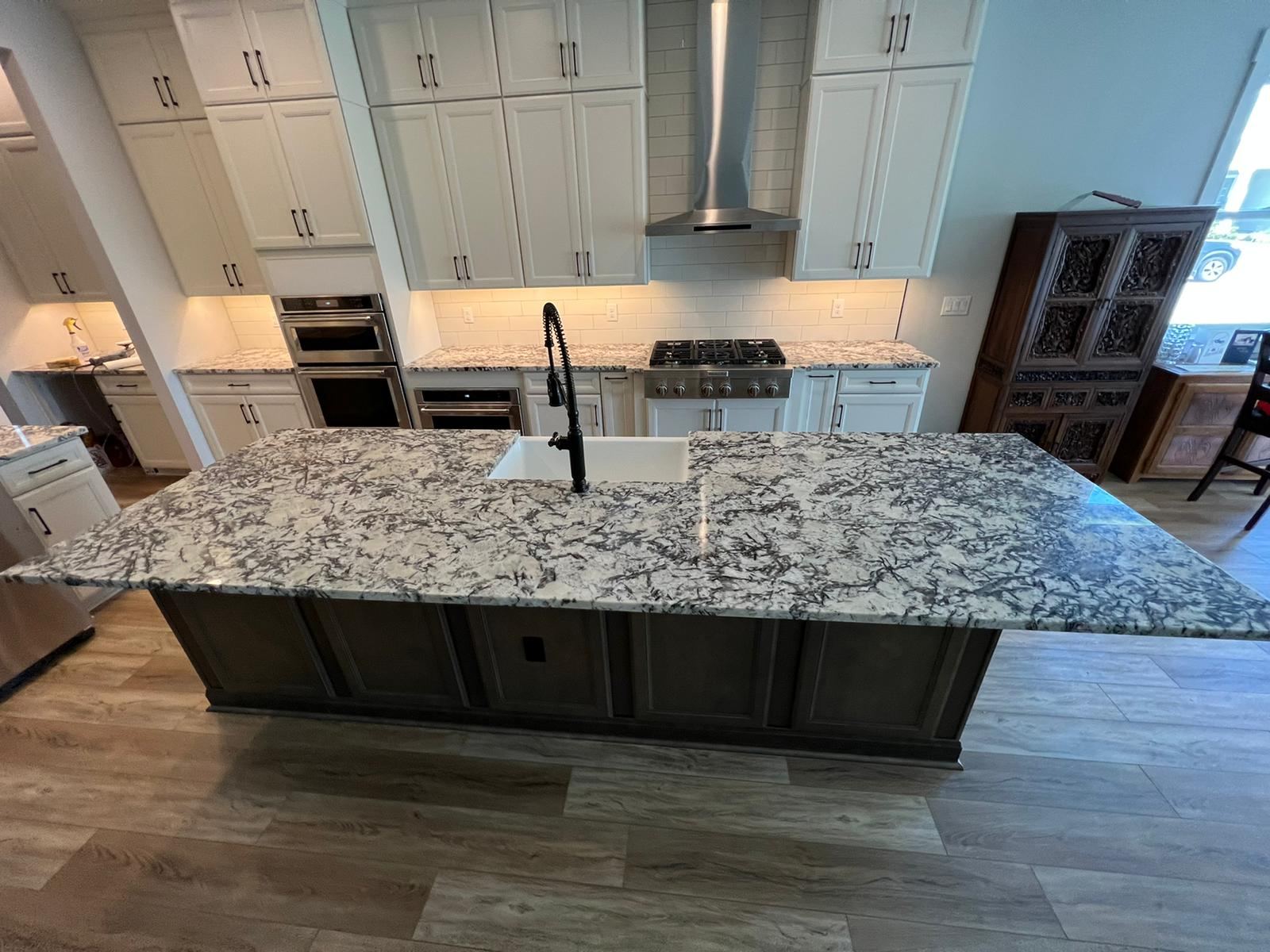 Completed kitchen with white cabinets and dramatic granite island